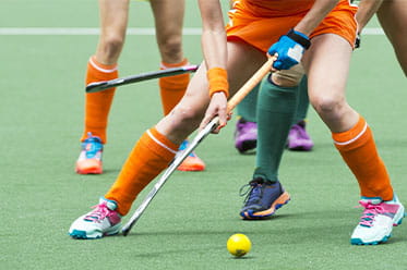 Field hockey players fight for position over the ball.