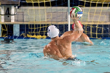A male water polo player takes a shot.