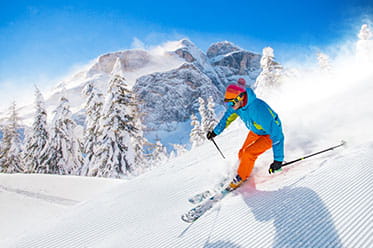 A freestyle skier carves across a combed slope.
