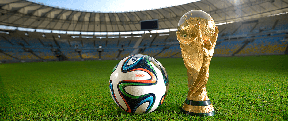 A ball and the World Cup trophy on a football pitch.