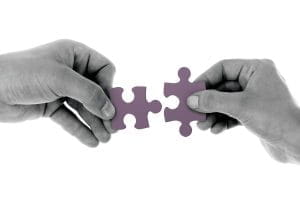 Two hands holding jigsaw pieces