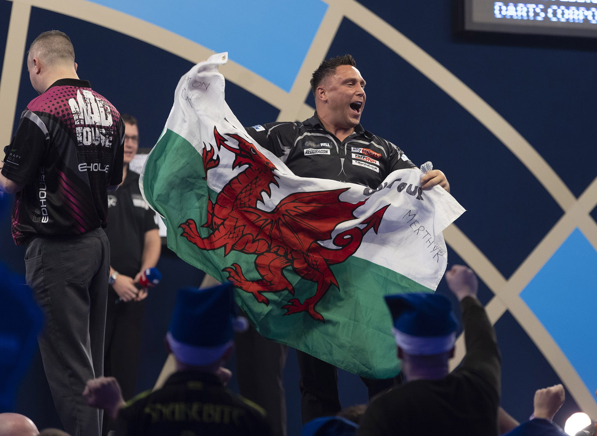 Gerwyn Price celebrates victory with a Welsh flag.  
