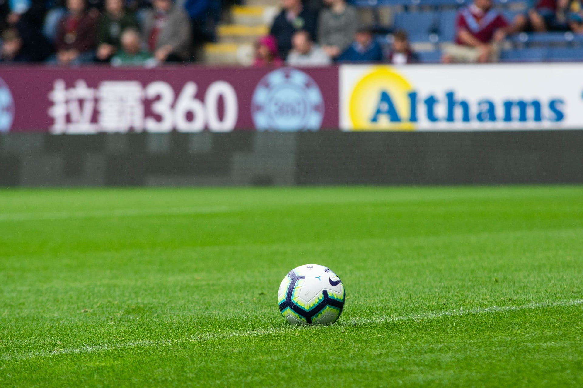 A picture of a football on the pitch with a gambling advertisement in the background.