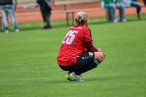 A picture of a female goalkeeper crouching on a pitch