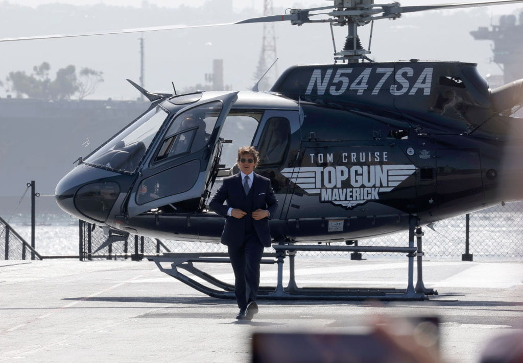 Tom Cruise arrives at a film festival in a helicopter branded to promote his new Top Gun movie.
