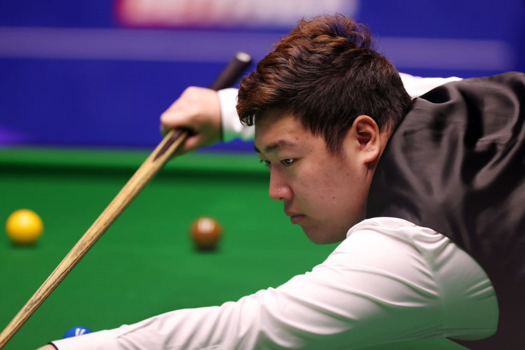 Yan Bingtao dari Tiongkok melakukan pukulan selama Kejuaraan Snooker Dunia 2022.