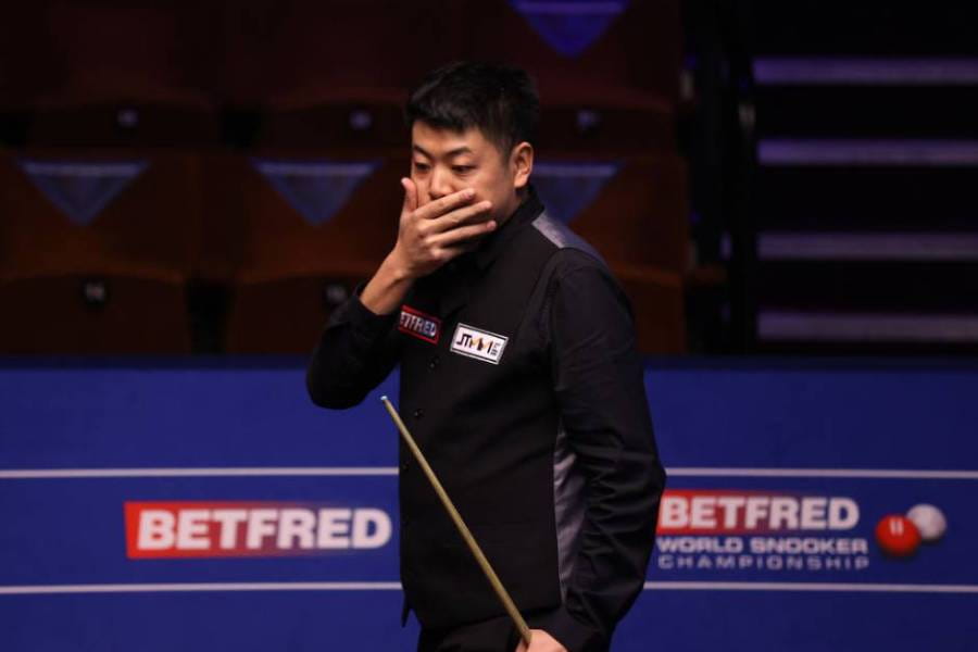 Liang Wenbo bereaksi terhadap tembakan yang buruk selama pertandingan di Kejuaraan Dunia Snooker 2021.