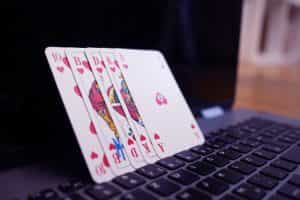 Poker cards next to a laptop