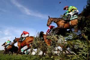 Horses stream over a famous spruce fence during the 2019 Grand National.