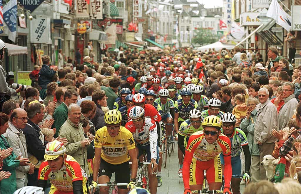 The peloton makes its way through crowded streets at the start of the 1996 Tour De France.