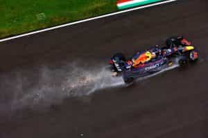 A Red Bull F1 car speeding down a wet straight.
