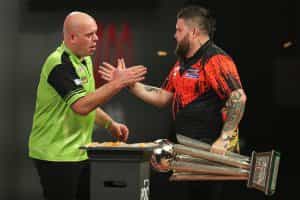 Michael Smith, holding his trophy, and Michael van Gerwen shake hands at the oche following the 2023 PDC World Championship.