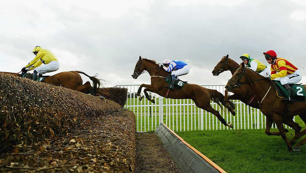 Horses jumping at open ditch at Towcester Racecourse.  