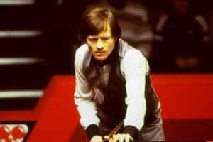 Alex Higgins assessing a shot at a snooker table.