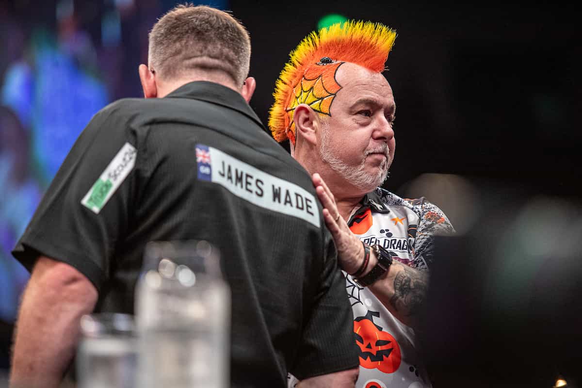 Peter Wright embraces fellow player James Wade on stage.