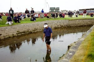 Jean Van De Velde of France looks at his ball in the burn on the 18th hole during the British Open.