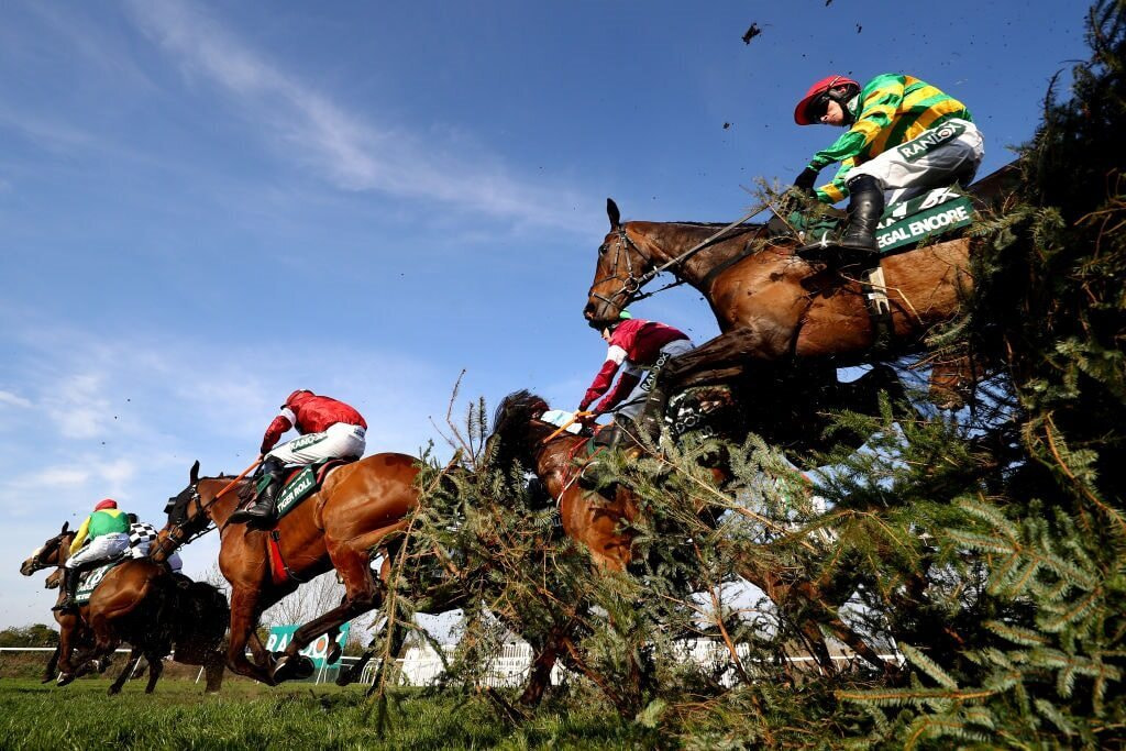 The field streaming over an Aintree fence during the 2019 Grand National.