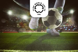 A dynamic close-up image of a footballer in action, about to strike a black-and-white football on a well-kept green pitch in a brightly lit stadium. The player's legs are shown wearing white football boots and socks, with the ball in mid-air near the sideline. Above the scene is the FIFA Club World Cup 25 logo, highlighting a significant football event.
