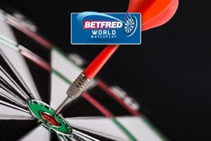 The image shows a close-up of a dartboard with a dart precisely hitting the bullseye. Above this scene is the logo for Betfred World Matchplay, suggesting a context related to a darts competition. The image captures the precision and skill associated with the sport.