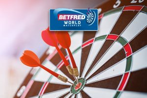 The image features a dartboard with three red darts accurately hitting the bullseye. Above the dartboard is the Betfred World Matchplay logo, indicating a connection to a notable darts competition. The scene highlights the precision and skill involved in the sport of darts.