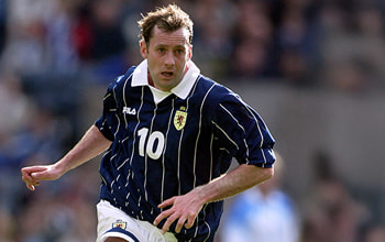 Don Hutchison, Scotland midfielder in a navy pin-striped No. 10 shirt sprinting forward during a match.