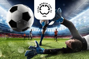 An exhilarating image capturing a dramatic moment in a football match, as a goalkeeper in black attire and blue gloves dives in an attempt to block a fast-approaching black-and-white football. In the background, other players are seen on a lush green pitch within a brightly lit stadium. Above the scene is the FIFA Club World Cup 25 logo, highlighting the event's prestige.