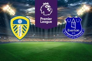 The image shows the logos of two Premier League football clubs, Leeds United and Everton, displayed on a football pitch background. The Leeds United logo is on the left side, featuring a shield with a white rose on top and blue and yellow stripes, along with the text 