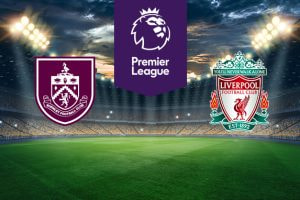 The image shows the logos of two football clubs, Burnley and Liverpool, displayed on a football pitch. The Burnley logo is on the left, featuring a maroon and white crest with various symbols and the text