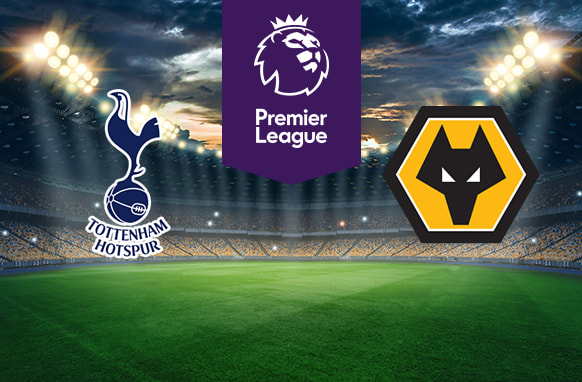 The image shows the logos of two football clubs, Tottenham Hotspur and Wolverhampton Wanderers, displayed on a football pitch. The Tottenham Hotspur logo is on the left, featuring a stylised cockerel standing on a football with the text "Tottenham Hotspur" below it. The Wolverhampton Wanderers logo is on the right, featuring a stylised wolf's head within a hexagonal shape with black, gold, and white colours. In the centre above the pitch is the Premier League logo, which includes a lion's head and the text "Premier League" below it on a purple background. The background depicts a stadium with dramatic lighting, creating an intense and vibrant atmosphere.