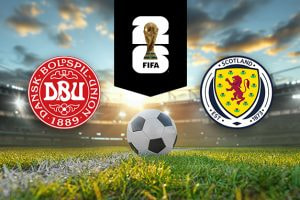 The image shows the logos of two national football associations, the Danish Football Association and the Scottish Football Association, displayed on a football pitch with a football in the centre. The Danish logo is on the left, featuring a red circular design with the text "Dansk Boldspil-Union" and "1889." The Scottish logo is on the right, featuring a yellow shield with a red lion and the text "Scotland" and "Est. 1873." In the centre above the football is the FIFA logo, which includes the FIFA World Cup Trophy and "FIFA" below it on a black background. The background depicts a stadium with dramatic sky lighting, creating a dynamic and intense atmosphere.