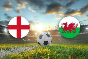 The image features two national football team logos on a football pitch. On the left, there is the flag of England, featuring a red cross of Saint George on a white background. On the right, there is the flag of Wales, which displays a red dragon passant on a green and white field. In the centre of the image, there is a football placed on the grass. The background depicts a stadium with a scenic sky showing a blend of clouds and sunlight, casting a warm, ambient glow over the scene. The overall composition creates an atmosphere of anticipation and excitement, highlighting the impending football match between the two nations.