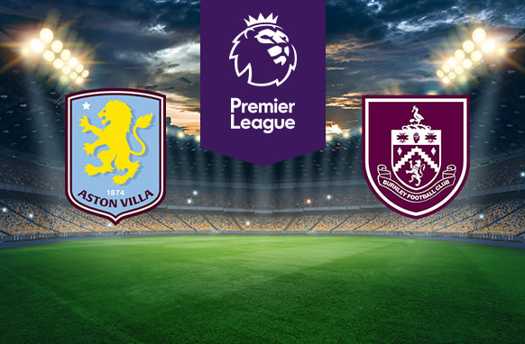 The image shows the logos of two football clubs, Aston Villa and Burnley, displayed on a football pitch. The Aston Villa logo is on the left, featuring a yellow lion on a light blue shield with the text "Aston Villa" and the year "1874" at the bottom. The Burnley logo is on the right, featuring a burgundy and white shield with various symbols, including a stork and a hand, with the text "Burnley Football Club" surrounding it. In the centre above the pitch is the Premier League logo, which includes a lion's head and the text "Premier League" below it on a purple background. The background depicts a stadium with dramatic lighting, creating an intense and vibrant atmosphere.