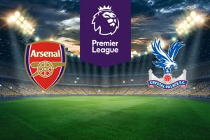 The image features two Premier League football team logos on a football pitch. On the left is Arsenal's logo, which features a cannon with the club's name above it on a red and gold shield-shaped badge. On the right is Crystal Palace's logo, displaying an eagle with its wings spread, perched on top of a football and the club's name below, with a ribbon and the year 1905 (when the club was founded). Above the logos in the centre is the Premier League logo with a stylised lion's head and the words "Premier League" on a purple background. The background shows a stadium with bright lights and a dramatic sky, creating an atmosphere of anticipation and excitement.