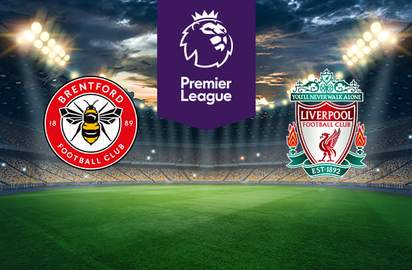 The image features two Premier League football team logos on a football pitch. On the left is Brentford's logo, which features a bee with the club's name and year of establishment (1889) encircling it on a red and white badge. On the right is Liverpool's logo, displaying a liver bird and the club's name, along with the motto "You'll Never Walk Alone" above it. The logo includes the year of foundation (1892) and decorative details. Above the logos in the centre is the Premier League logo with a stylised lion's head and the words "Premier League" on a purple background. The background shows a stadium with bright lights and a dramatic sky, creating an atmosphere of anticipation and excitement.