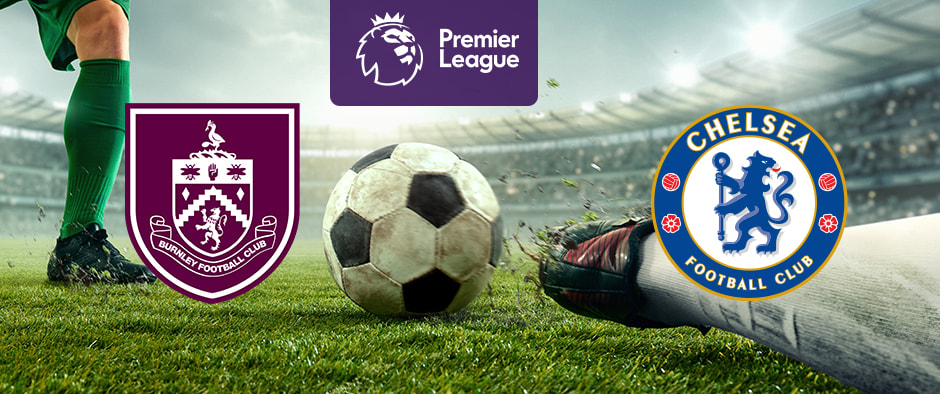 The image features logos representing two football clubs participating in a Premier League match. On the left is the logo of Burnley Football Club, which includes a shield with various symbols and a claret and blue colour scheme. On the right is the logo of Chelsea Football Club, featuring a blue lion holding a staff with red roses and footballs around the edge. Above the logos is the Premier League logo, featuring a lion's head with a crown and the text "Premier League" beneath it. The background shows a football pitch with close-up action involving players' legs and a football, creating an atmosphere of competition and excitement. The stadium is filled with spectators, enhancing the feeling of anticipation for the match.